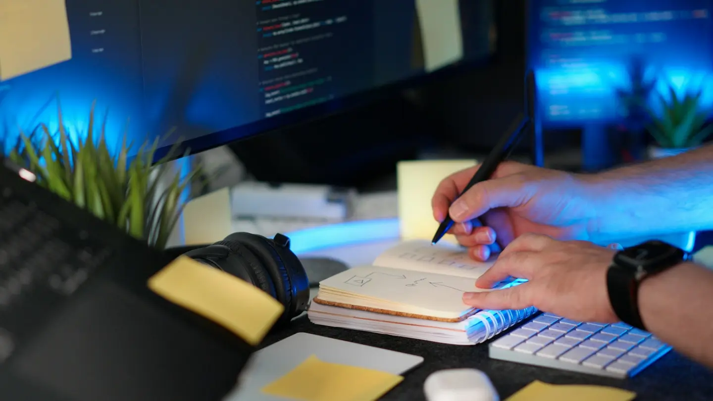 Pessoa programando enquanto organiza anotações de projeto